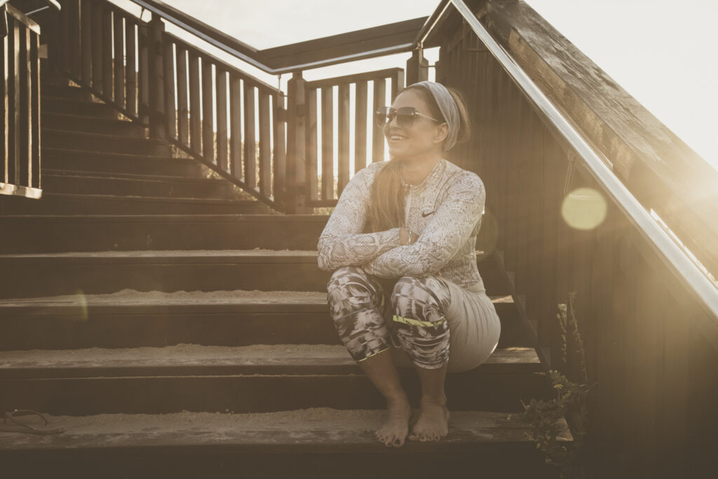 Photo of a woman with sunglasses sitting on a staircase and looking at the sky