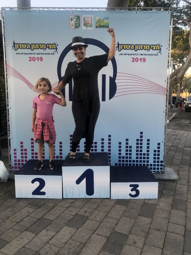 Photo of Get Fit Ima on a podium with a young girl celebrating
